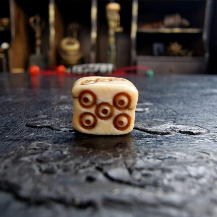 Hand-carved bone dice bead with traditional ritual markings.
