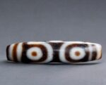 Authentic Tibetan 6-Eye Dzi bead featuring distinct circular patterns on dark etched agate.