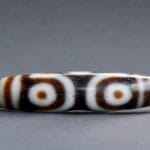 Authentic Tibetan 6-Eye Dzi bead featuring distinct circular patterns on dark etched agate.