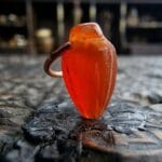 Ancient carnelian bead featuring a deep translucent orange hue and natural ritual wear.