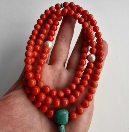Hand-knotted red coral beads necklace with a central hand-carved pearl skull pendant.