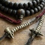 Hand-carved antique Tibetan kapala bone mala counters on a weathered 108 Rudraksha seed prayer necklace.