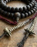 Hand-carved antique Tibetan mala counters on a weathered 108 Rudraksha seed prayer necklace.