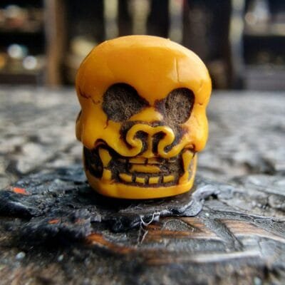 Hand-carved Chittipati bone bead with a detailed dancing skeleton motif.