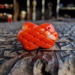 Hand-carved red coral bead featuring a traditional infinity knot.