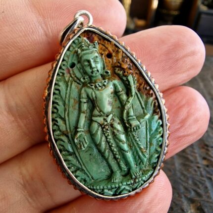 Handcrafted Tibetan Ghau locket featuring a central Avalokiteshvara figure inlaid with turquoise.