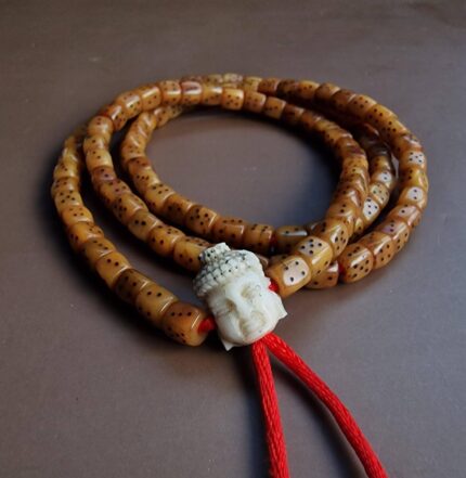 Hand-carved bone mala beads shaped like dice with traditional Tibetan numbering and a Buddha head.