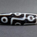 Hand-etched 9-eye Dzi bead featuring traditional sacred geometry.
