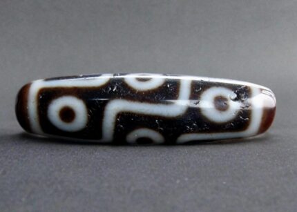 Hand-etched 9-eye Dzi bead featuring traditional sacred geometry.