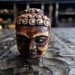 Hand-carved Buddha head amulet featuring a serene expression and weathered ritual patina.