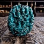 A vibrant blue Tibetan turquoise amulet carved into the traditional skeletal face of a Chitipati protector.