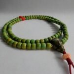 Close-up of 108-bead Tibetan green turquoise mala necklace with red coral accents and gold-filled spacers