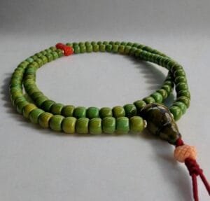 Close-up of 108-bead Tibetan green turquoise mala necklace with red coral accents and gold-filled spacers