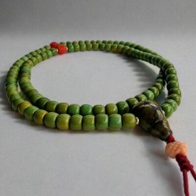 Close-up of 108-bead Tibetan green turquoise mala necklace with red coral accents and gold-filled spacers