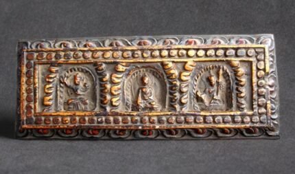 Hand-carved 19th-century Tibetan wooden scripture cover with three detailed Buddha figures.