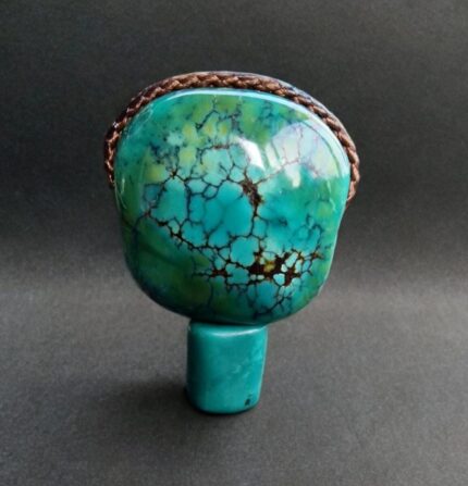 Detailed shot of a natural Tibetan turquoise guru bead showing the traditional three-hole drilling for mala stringing.