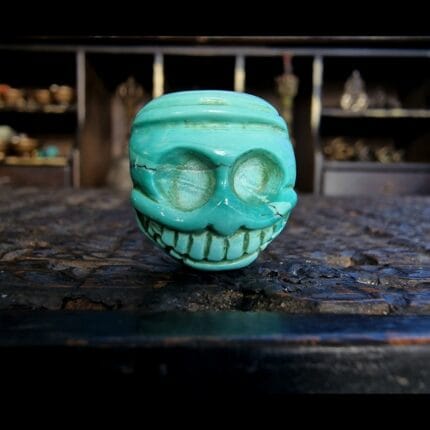 Tibetan Turquoise Chitipati bead hand-carved skull with grinning teeth and natural turquoise veins.